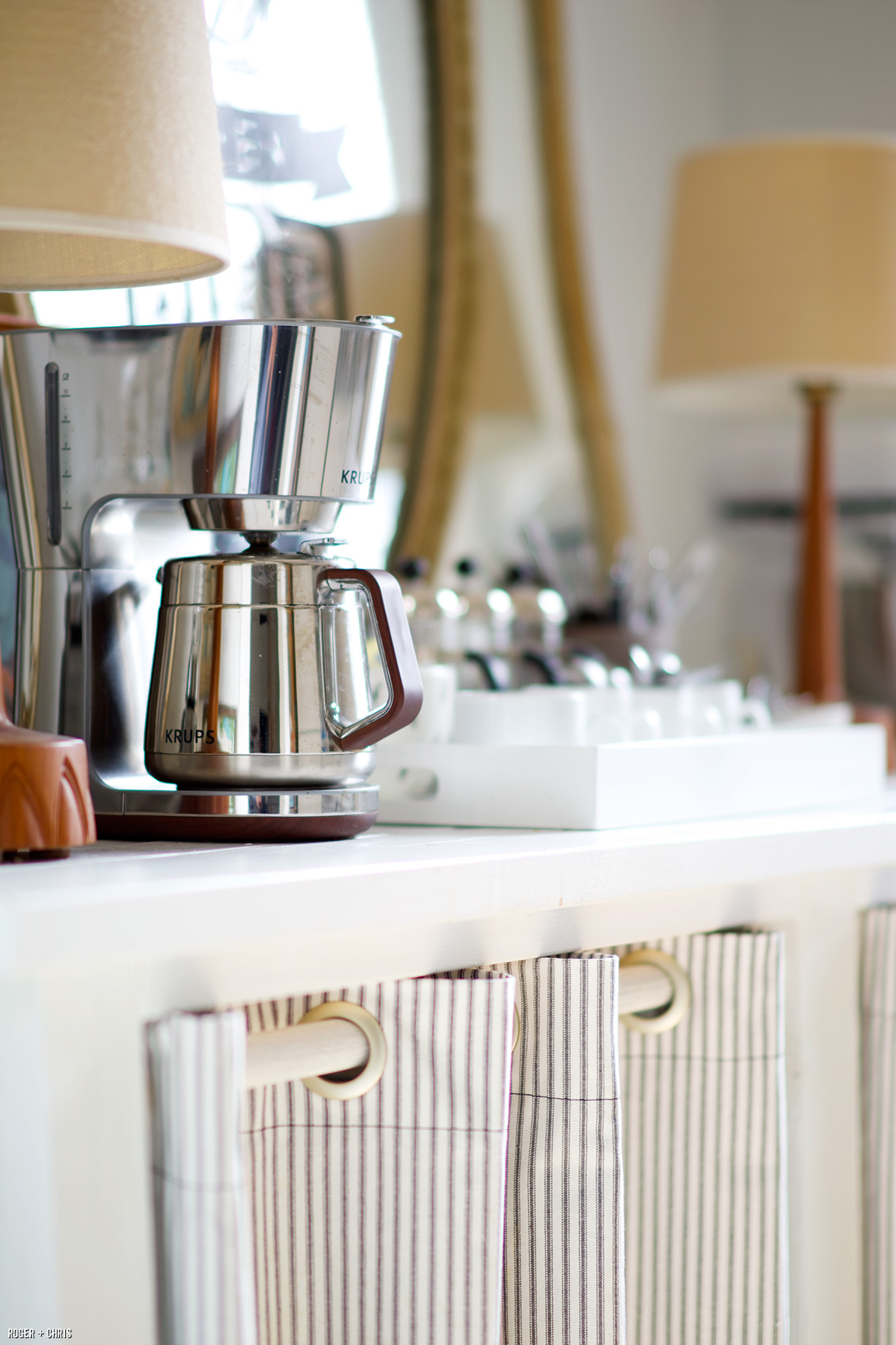 The coffee maker and cups sit atop the pantry table.